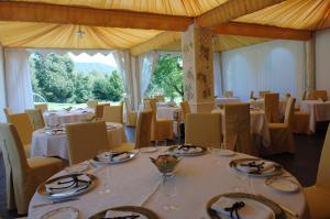 una sala da pranzo con tavoli e sedie bianchi e una tavola di La Locanda Del Notaio a Pellio Inferiore