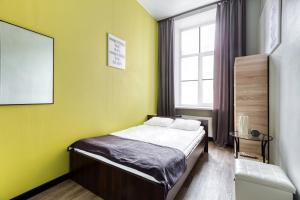 a bedroom with a bed with yellow walls and a window at Nomera na Sadovoy in Saint Petersburg