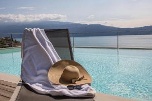 a hat sitting on a chair next to a swimming pool at Exclusive Villa Agave in Toscolano Maderno
