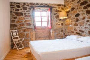 a bedroom with a bed and a window and a chair at Casa do Manel in Trancoso