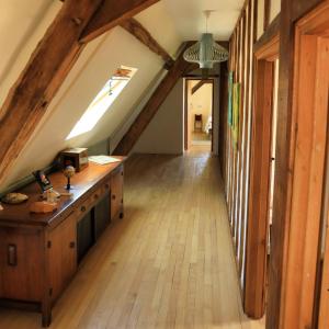 um corredor no sótão com piso em madeira e uma janela em Le cottage du séquoia em Chamberet
