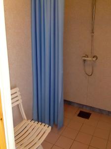 a blue shower curtain in a bathroom with a chair at Fjorden Campinghytter in Geiranger