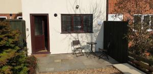 uma pequena casa branca com uma porta e duas cadeiras em Seashells Cottage em Lytham St Annes