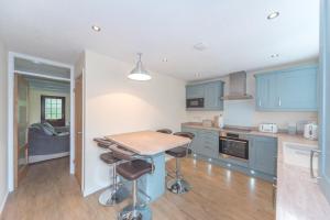 eine Küche mit blauen Schränken, einem Tisch und Stühlen in der Unterkunft Seashells Cottage in Lytham St Annes + 7 Fotos