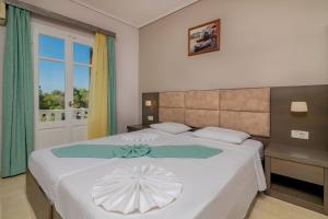 Plaka Beach Resort في فاسيليكوس: غرفة نوم بسرير ابيض كبير عليها مظلة بيضاء