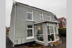 a gray house with large windows on a street at Glen View a Stones Throw away from The Gower! in Swansea
