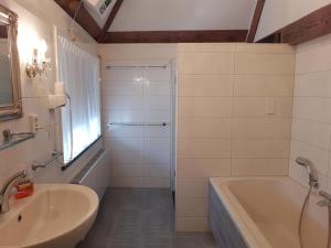 a bathroom with a bath tub and a sink at VRYE HEERLYKHEYD ( adults only ) studio 3 in Middelburg