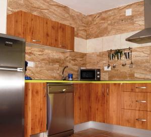 La cuisine est équipée d'armoires en bois et d'un réfrigérateur en acier inoxydable. dans l'établissement El Volvedero, à Castillo