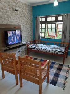 a room with a bed and a tv and a bench at Casa Beija-Flor in Trindade