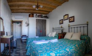 a bedroom with two beds and a wooden ceiling at Casa Rural La CasAna in Fuente del Arco