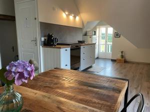 a kitchen with a wooden table and a vase with purple flowers at Gîte Le Domaine d Orphée in Marmagne