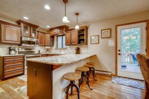 a kitchen with wooden cabinets and a island with bar stools at Casa de Montagne Home: High-End Log Home, Downtown Frisco in Frisco +33 photos