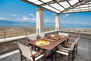 een tafel en stoelen op een balkon met uitzicht op de oceaan bij Marini Luxury Apartments and Suites in Aegina Town