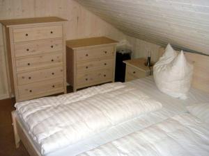a bedroom with a white bed and two dressers at Ferienhaus-Kinderlieb in Baabe