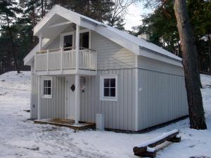 a small white building with a balcony in the snow at Ferienhaus-Kinderlieb in Baabe
