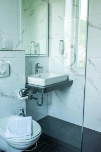 a white bathroom with a sink and a toilet at Swiss Plus Hotel in Bihać