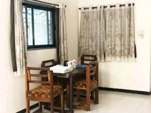 a dining room table with chairs and a window at villas holiday family home service in Surat