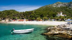 a boat in the water next to a beach at Apartments Plazibat in Hvar