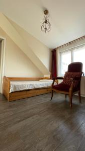 a bedroom with a bed and a chair and a window at Le Grand Chalet in Bagnoles de l'Orne