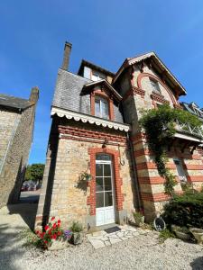 an old brick building with a white door at Le Grand Chalet in Bagnoles de l'Orne