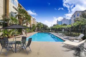 a swimming pool with chairs and a table and an umbrella at Baymont by Wyndham Orlando-International Dr-Universal Blvd in Orlando