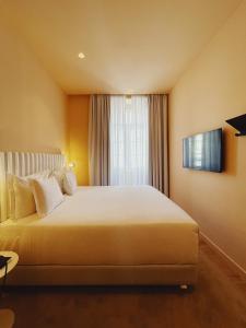 a bedroom with a large white bed with a window at Esqina Cosmopolitan Lodge in Lisbon