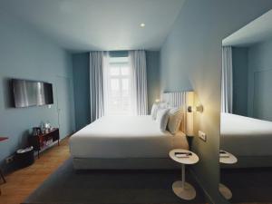 a bedroom with a large white bed and a window at Esqina Cosmopolitan Lodge in Lisbon