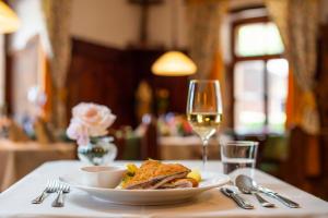 a plate of food and a glass of wine on a table at Traditionsgasthof Weißbacher in Auffach