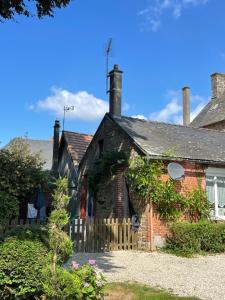 an old brick house with a wooden fence at Le Petit Chalet in Bagnoles de l'Orne