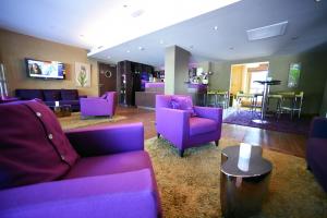 a living room with purple couches and a table at Hôtel Les Rives in Guebwiller
