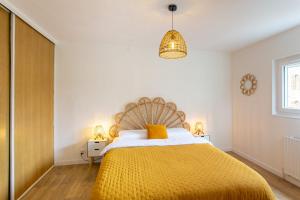 a bedroom with a bed with a yellow blanket at La Vénus de Renancourt - face au Zénith, Licorne, Mégacité in Amiens