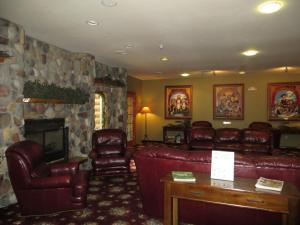uma sala de estar com mobiliário de couro e uma lareira de pedra em Cranberry Country Lodge em Tomah