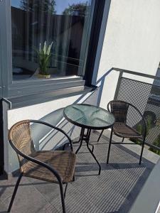 patio z 2 krzesłami i stołem na balkonie w obiekcie Apartamenty Prima w Poddąbiu