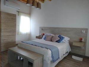 um quarto com uma grande cama branca com almofadas azuis em CAYE Guest House em Tunuyán