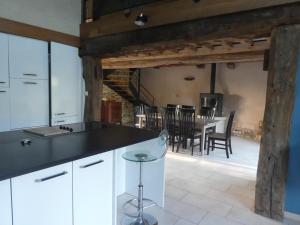 a kitchen with white cabinets and a dining room with a table at Gite de la Motte in Litteau