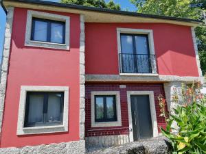 a red house with windows and a balcony at Casinha da Mó in Vieira do Minho