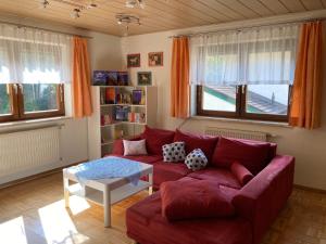 a living room with a red couch and a table at Ferienhaus Elisabeth Selbstversorger Unterkunft in Sankt Aegyd am Neuwalde