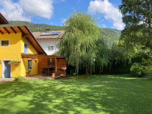 a house with a large yard with a tree at Ferienhaus Elisabeth Selbstversorger Unterkunft in Sankt Aegyd am Neuwalde