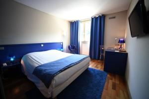 a bedroom with a bed with blue curtains and a television at Hotel Du Lac in Guebwiller
