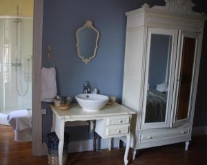 La salle de bains est pourvue d'un lavabo blanc et d'un miroir. dans l'établissement L'Entrée Chambres d'Hôtes Bar & Restaurant, à Castillonnès