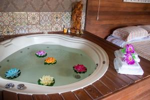 eine Badewanne mit Blumen in einem Zimmer mit einem Bett in der Unterkunft Shiva Guest House in Florianópolis