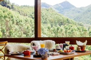 a table with food on it with a view of mountains at Flor de Café Pousada in Pedra Menina