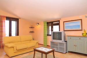 a living room with a yellow couch and a tv at La dimora del Sole in Scicli