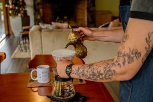 a man with tattoos on his arms holding a coffee maker at Flor de Café Pousada in Pedra Menina