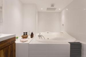 a white bathroom with a tub and a sink at Ayenda La Joya in Mexico City