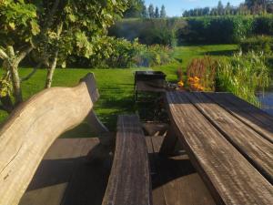 two wooden benches sitting in a garden with a field at Mikalojiskis in Inturkė