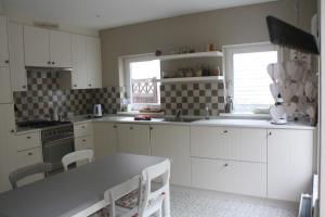a kitchen with white cabinets and a table with chairs at dreamingzeeland in Nieuwvliet