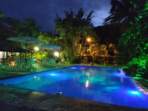 ein Pool bei Nacht mit Tischen und Sonnenschirmen in der Unterkunft Charmosa casa com churrasq na praia de Camburi in São Sebastião