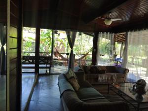 ein Wohnzimmer mit einer Couch und einigen Fenstern in der Unterkunft Charmosa casa com churrasq na praia de Camburi in São Sebastião