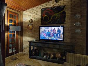 ein Wohnzimmer mit einem Fernseher an einer Ziegelwand in der Unterkunft Charmosa casa com churrasq na praia de Camburi in São Sebastião